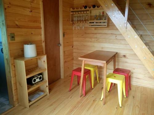 a wooden room with a table and four stools at Hermosa cabaña con vista al lago Vichuquén in Vichuquén