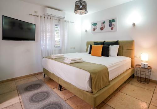 1 dormitorio con 1 cama grande y TV de pantalla plana en YalaRent Fruit Tree Villa with Private Pool, en Eilat