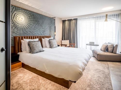 ein Schlafzimmer mit einem großen weißen Bett und einem Sofa in der Unterkunft Alexander Hotel in Noordwijk aan Zee