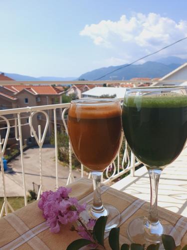 dos copas de vino sentadas en una mesa en un balcón en Apartments Maxim en Tivat