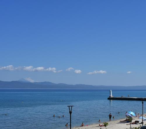 a beach with people in the water and a dock at Sunset studio in Pefkohori