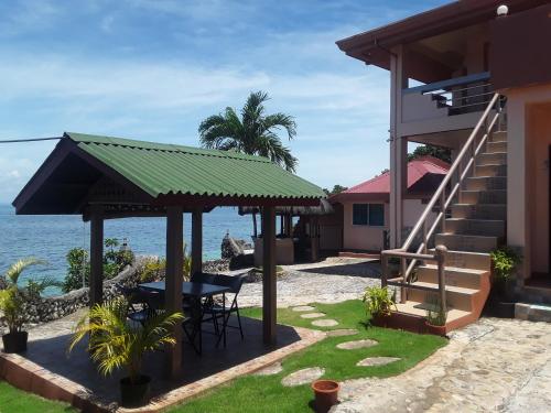 ein Haus mit einem Tisch und Stühlen am Meer in der Unterkunft Sunset Vista Sea Front Guest House in Camotes Islands