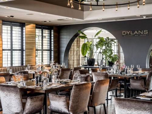 een restaurant met tafels en stoelen in een kamer met ramen bij Alexander Hotel in Noordwijk aan Zee