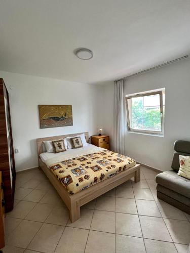 een slaapkamer met een bed, een raam en een bank bij Apartmani Cinci in Tivat