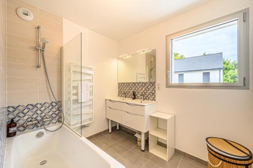 uma casa de banho com uma banheira, um lavatório e uma janela em RETOUR DE PLAGE - Maison familiale à 400 m de la plage! em Arradon