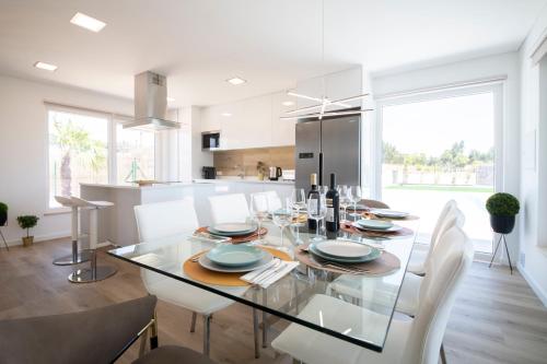 a dining room and kitchen with a glass table and chairs at Monte Calmaria by Estilo Lusitano, with private pool and Jacuzzi in Grândola