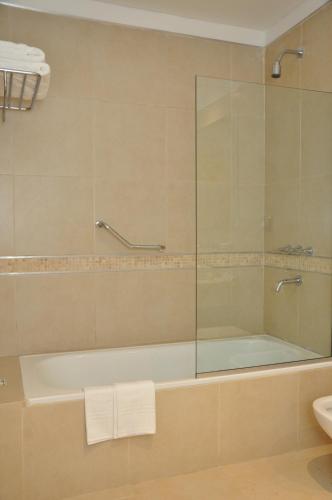a bathroom with a tub and a glass shower at Howard Johnson Hotel Piedras Moras in Almafuerte