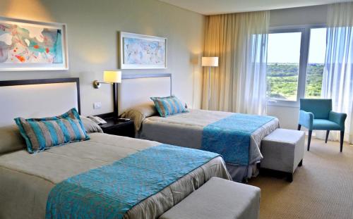 a hotel room with two beds and a chair at Howard Johnson Hotel Piedras Moras in Almafuerte