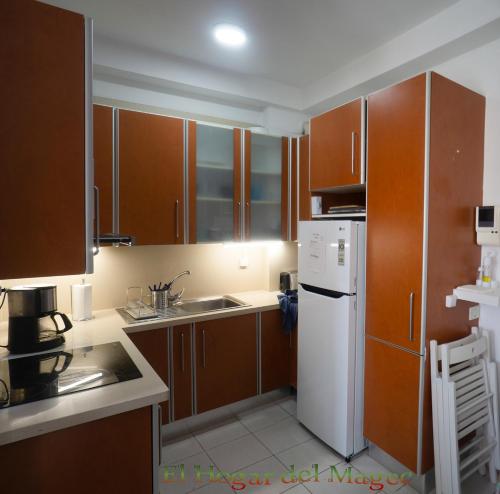 a kitchen with wooden cabinets and a white refrigerator at EL HOGAR DEL MAGEC in Las Palmas de Gran Canaria