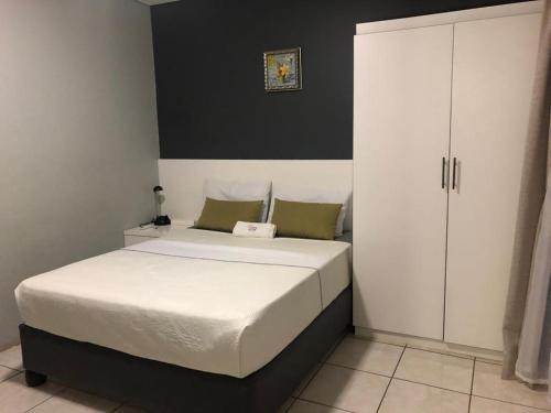 a bedroom with a white bed and a white cabinet at Homey Guesthouse in Gaborone