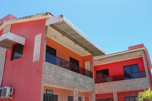 an orange and red building with a balcony at Casa Lua Nova na Praia de Peroba, Maragogi in Maragogi