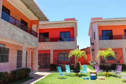 a yard with chairs and palm trees in front of a building at Casa Lua Nova na Praia de Peroba, Maragogi in Maragogi