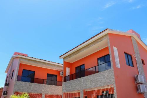 an orange apartment building with a blue sky in the background at Casa Lua Nova na Praia de Peroba, Maragogi in Maragogi