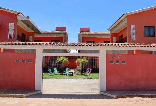 a red building with a gate in front of a yard at Casa Lua Nova na Praia de Peroba, Maragogi in Maragogi