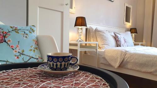 a coffee cup on a table in a bedroom at Apartament Przy Starówce - Bella in Bolesławiec