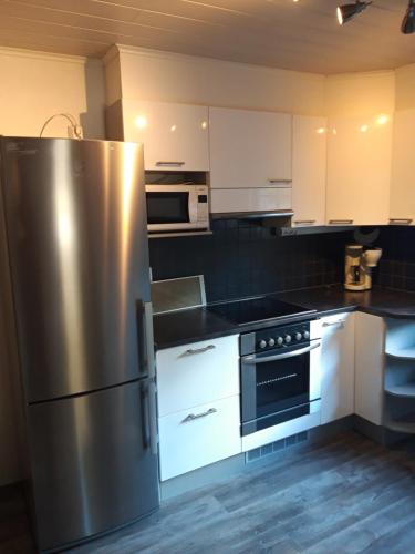 a kitchen with a stainless steel refrigerator and white cabinets at Jaalan Tienristi in Kouvola