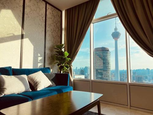 ein Wohnzimmer mit einem blauen Sofa und einem großen Fenster in der Unterkunft De Sky Suites KLCC Kuala Lumpur in Kuala Lumpur