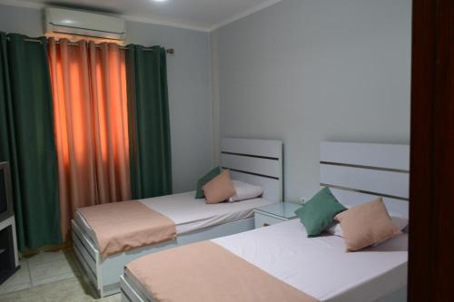 twee bedden in een kamer met groene en oranje gordijnen bij شقه مفروشه 3 غرف امام سيتي ستارز in Caïro