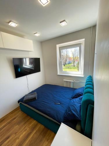 a bedroom with a blue bed and a flat screen tv at Tvarkingas butas Klaipedos centre in Klaipėda