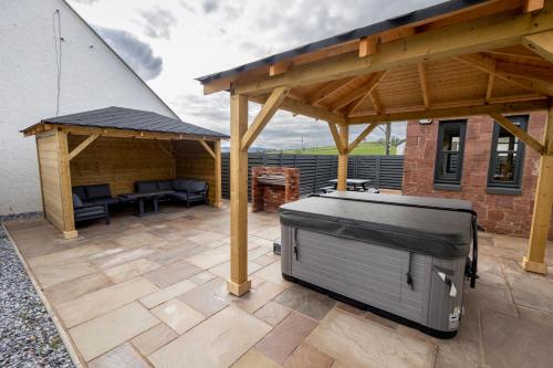 a patio with a barbecue grill and a pavilion at Westertonhill Lodge - 3 Double Bedrooms Sleeps 8 With Private Hot Tub Hire Available in Balloch