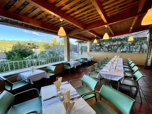 a restaurant with white tables and green chairs at Hotel Berneron in Vallon-Pont-dʼArc