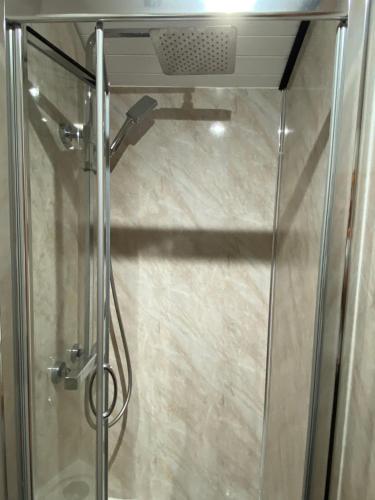 a shower with a glass door in a bathroom at Luxury Railway carriage with own private hot tub in Clodock
