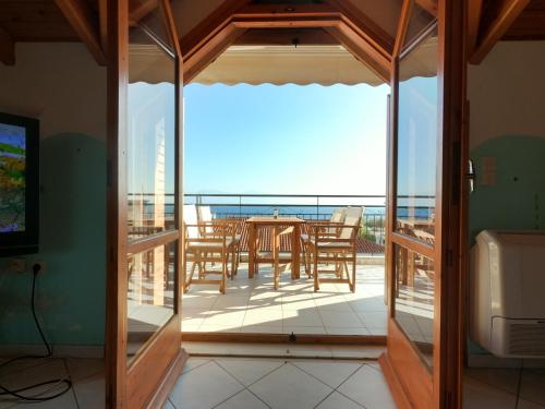 a room with a balcony with a table and chairs at Loft apartment 20m from sea in Melission