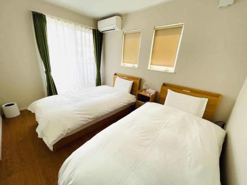 藤澤的住宿－Fujisawa - House - Vacation STAY 88722，配有白色床单和窗户的客房内的两张床