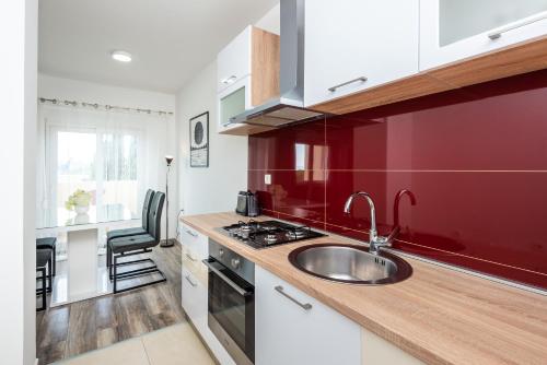 een keuken met een wastafel en een rode muur bij Apartment Tina in Ploče