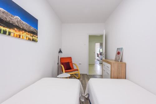 um quarto com 2 camas e uma cadeira laranja em Apartment Tina em Ploče