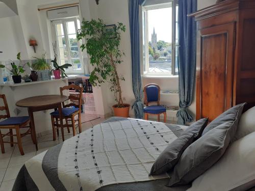 a bedroom with a bed and a table and chairs at Studio De La Mer in Arromanches-les-Bains