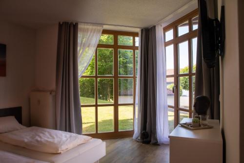 a bedroom with a bed and a large window at Feriendorf Glasgarten in Rötz