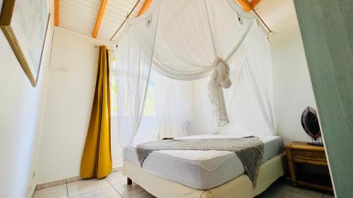 um quarto com uma cama de dossel e uma janela em Île tropical lodges em Sainte-Anne