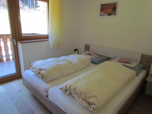 two beds sitting in a room with a window at Oeberst-hof in Sarntal