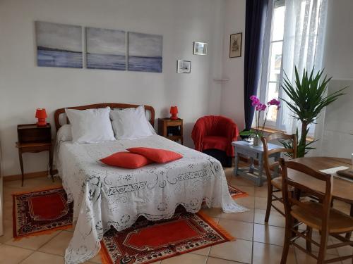 ein Schlafzimmer mit einem Bett mit roten Kissen darauf in der Unterkunft Studio Neptune in Arromanches-les-Bains