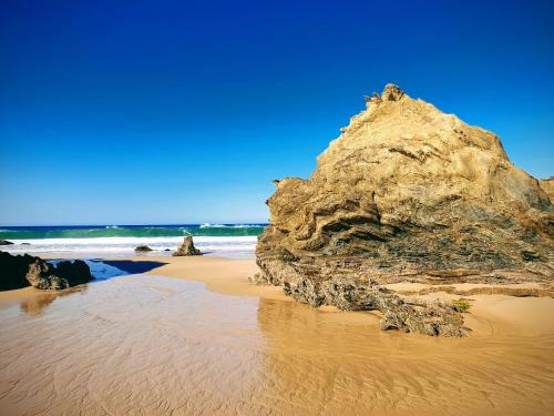 a large rock on a sandy beach with the ocean at Monte Calmaria by Estilo Lusitano, with private pool and Jacuzzi in Grândola