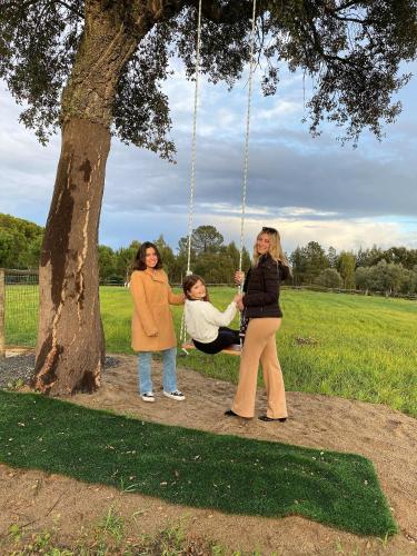 three women on a swing under a tree at Monte Calmaria by Estilo Lusitano, with private pool and Jacuzzi in Grândola