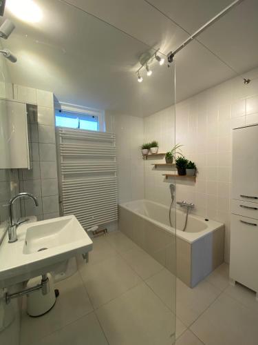a white bathroom with a tub and a sink at Vakantiewoning in Middelburg Zeeland in Middelburg