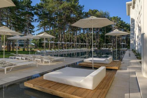 a swimming pool with white lounge chairs and umbrellas at Ensana Aquahouse in Saints Constantine and Helena