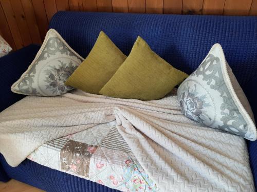 a blue couch with pillows and a blanket at Cozy Chalet by Interlaken. Parking in Ringgenberg