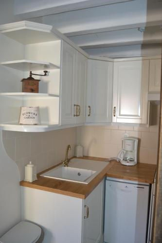 une cuisine avec des armoires blanches et un évier dans l'établissement Gite Art&Mie à l’entrée du Parc de CHAMBORD, à Huisseau-sur-Cosson