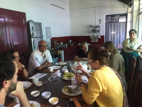 a group of people sitting around a table eating at Walton's Homestay, Fort Cochin in Fort Kochi