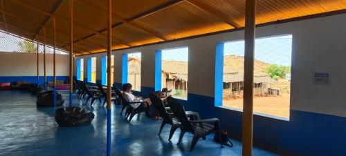 a person sitting at a table in a room with windows at HosteLife Gokarna in Gokarna