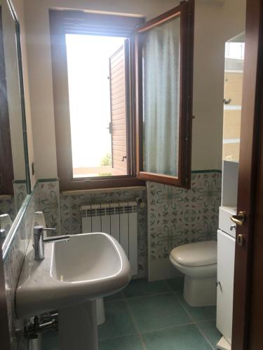 een badkamer met een wastafel, een toilet en een raam bij B&B Regina Viarum in Minturno