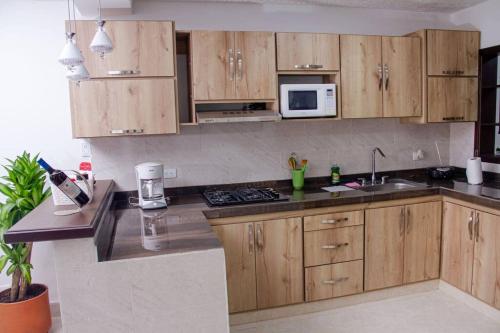 a kitchen with wooden cabinets and a sink and a microwave at Apartamento confortable, cerca a la Basílica in Buga