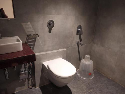 a bathroom with a white toilet and a sink at Hotel Adams Inn Near Mumbai Airport in Mumbai