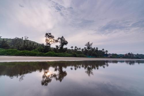 a body of water with trees in the background at Amadi Beach Front Resort in Mandrem
