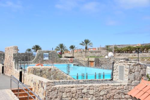 a swimming pool in a resort with a stone wall at ELSA TAURO TOPAZ in Mogán