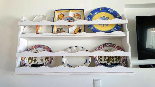 a white shelf filled with plates and bowls at Ma mer in Naxos Chora