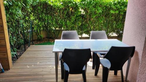 einen Tisch mit vier Stühlen auf einer Holzterrasse in der Unterkunft Superbe appartement dans résidence avec piscine in Toulouse